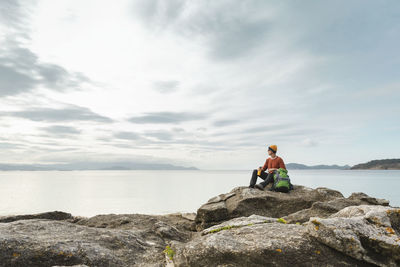 Man exploring the coast sitting on the rocks