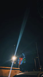 Illuminated ferris wheel against sky at night