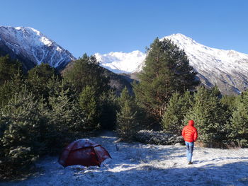 Rear view of person on snowcapped mountain against sky