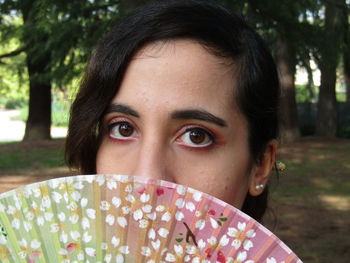 Close-up portrait of young woman with hand fan