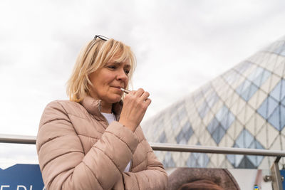 Low angle view of woman using vape against sky