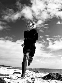 Full length of woman running on beach against sky