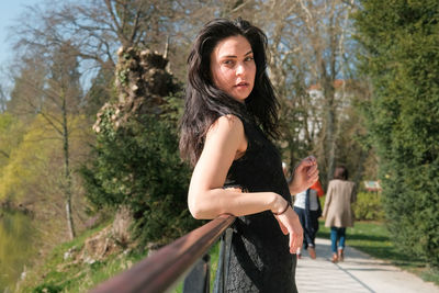 Portrait of young woman standing against trees