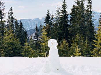 One big snowman and one little snowman with forest of evergreen trees and mountains