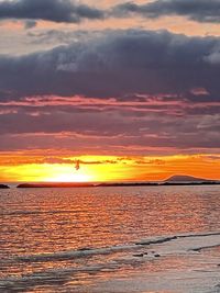 Scenic view of sea against dramatic sky during sunset