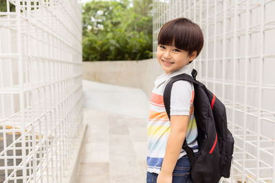Portrait of smiling boy standing against railing