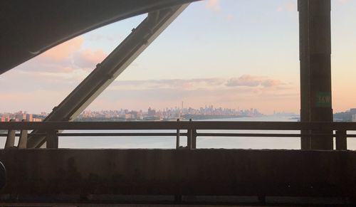 Bridge over river in city against sky during sunset