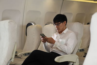 Young man using mobile phone while sitting in bus