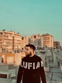 Portrait of young man standing against buildings