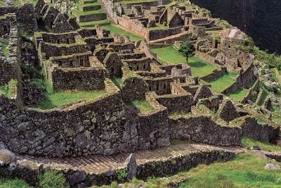 Stone walls ruins from houses on a slope forming the ancient inca city of machu picchu, in peru.