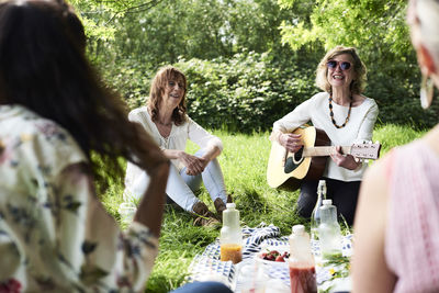 Group of women with guitar having fun at a picnic in park