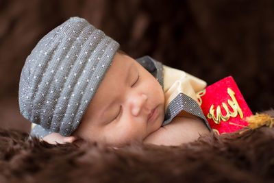 Close-up portrait of cute boy lying in hat