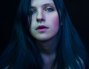 Close-up portrait of beautiful young woman over black background