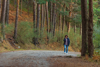 Full length of man standing on road amidst trees in forest