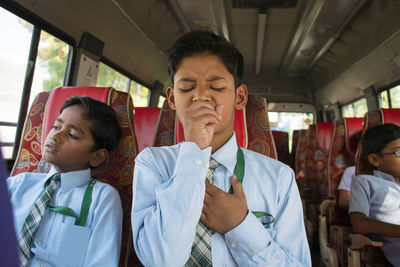 Close-up of boy coughing in school bus