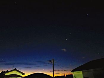 Low angle view of silhouette electricity pylon against sky at night