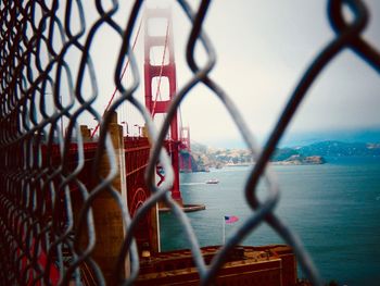 Metal fence by city against sky