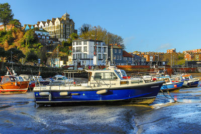 Boats moored in sea against buildings in city