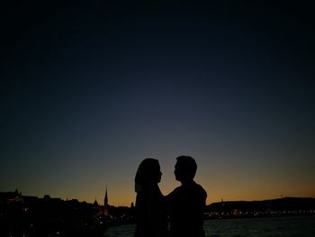 Silhouette couple at danube river against sky during dusk