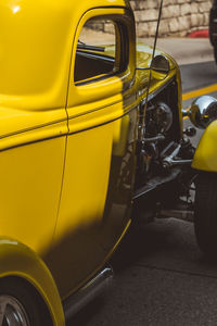 Close-up of yellow car on road