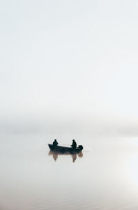 People on boat in sea against sky