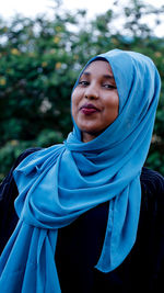 Portrait of woman wearing blue hijab against tree