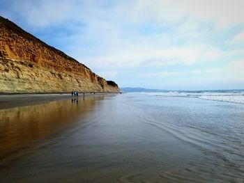 Scenic view of beach against cloudy sky