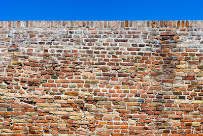 Low angle view of brick wall against building