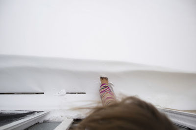 Overhead view of girl touching snow with foot