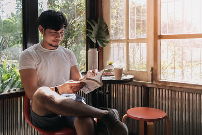 Young man using mobile phone while sitting on table