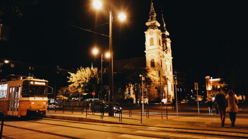 People at illuminated city against sky at night