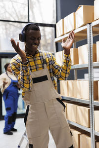 Side view of young man with arms outstretched standing in city