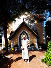 Woman standing by tree against built structure