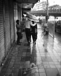 Rear view of people walking on footpath in city