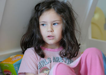 Expressive young girl sitting in her toy box