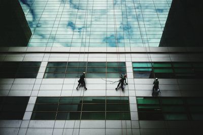 Low angle view of workers on glass building
