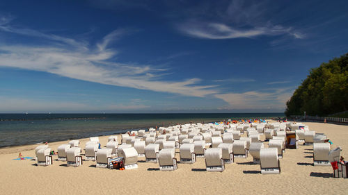 Hooded chairs on beach against sky