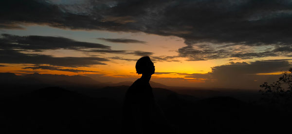 Silhouette man standing against orange sky