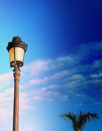 Low angle view of illuminated street light against blue sky