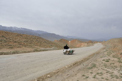 Man on motorcycle on road against sky