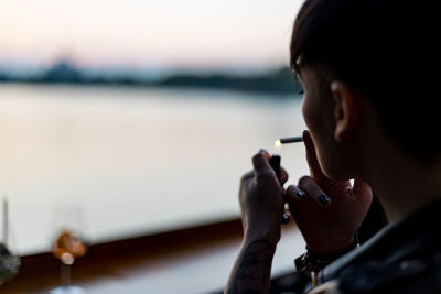 Close-up of woman hand holding water against sky
