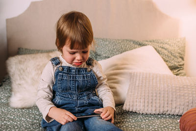 Side view of boy sitting on sofa at home