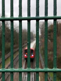 Close-up of railroad track seen through chainlink fence