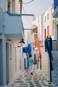 Rear view of woman walking on alley amidst buildings