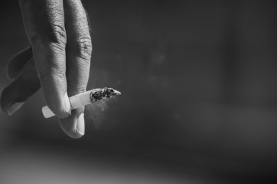 Cropped hand of person holding cigarette outdoors