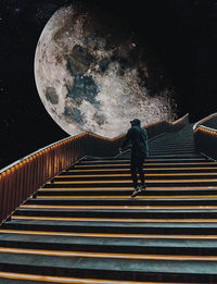 Rear view of man walking on staircase at night