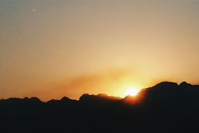 Scenic view of silhouette mountains against orange sky