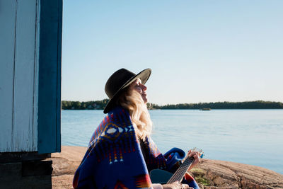 Woman sat taking in vitamin d whilst playing the guitar at the beach