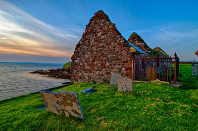 Built structure on beach against sky during sunset