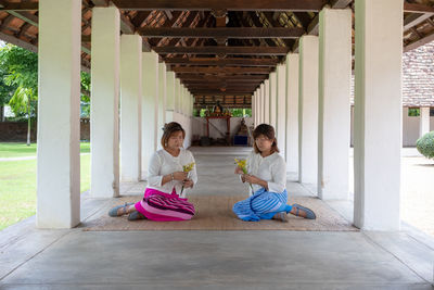 Full length of women sitting on floor in building